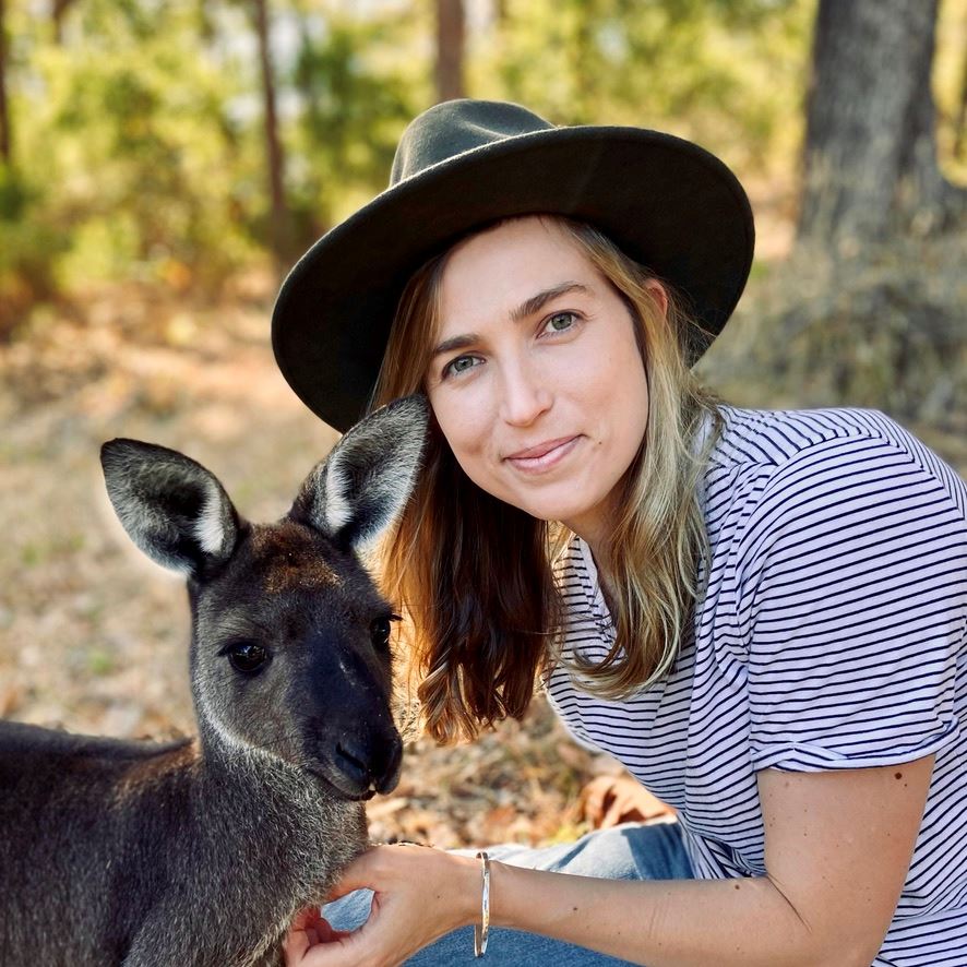 Amy in a hat petting a kangaroo.